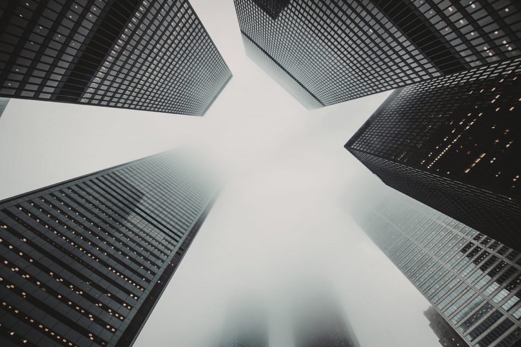 Moderne Hochhäuser im Nebel aus extremer Perspektive, Symbol für überdimensionierte Projektplanung ohne klare Struktur